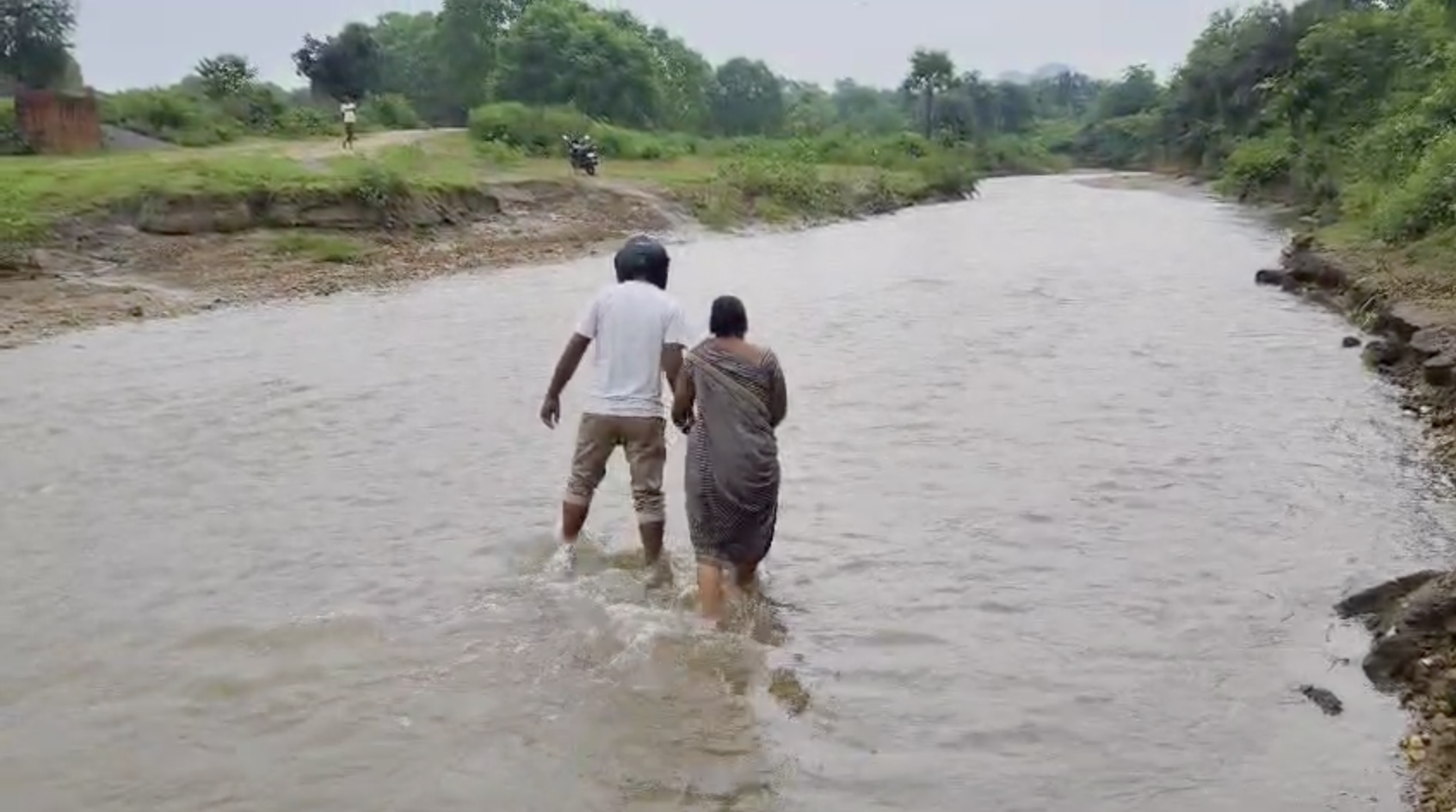 डायवर्जन रोड टूट जाने से पैदल नदी पार करते ग्रामीण।