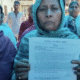 घर खाली करने से जुड़ा नोटिस दिखाती एक महिला।