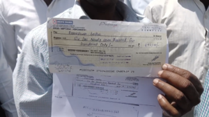 फ्रॉड कंपनी में किए निवेश का चेक दिखाता एक पीड़ित।